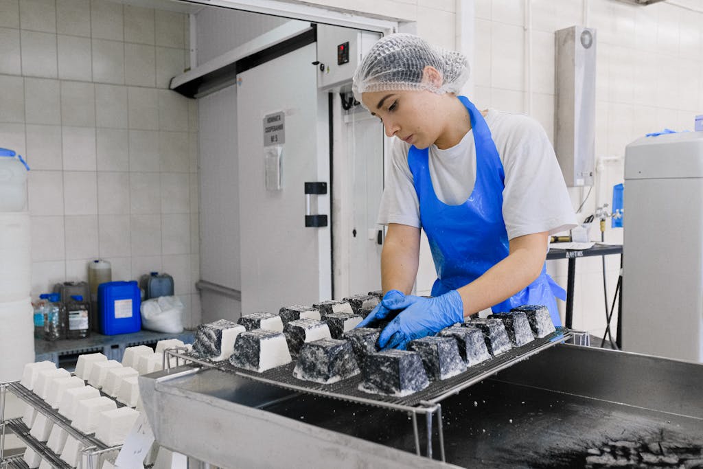 A worker in a cheese factory examines cheese blocks during production, focusing on quality control.